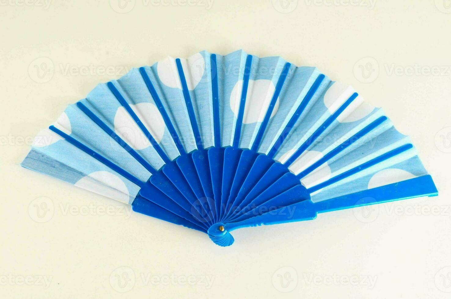a blue and white polka dot fan with a handle photo