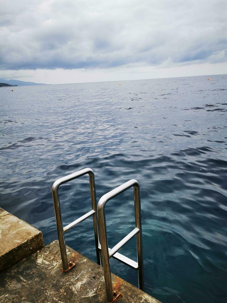 Photo of a metal railing in the middle of a serene body of water