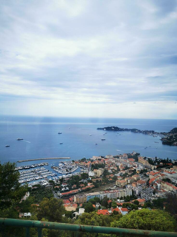 Photo of a panoramic view of a city and the ocean from a hilltop