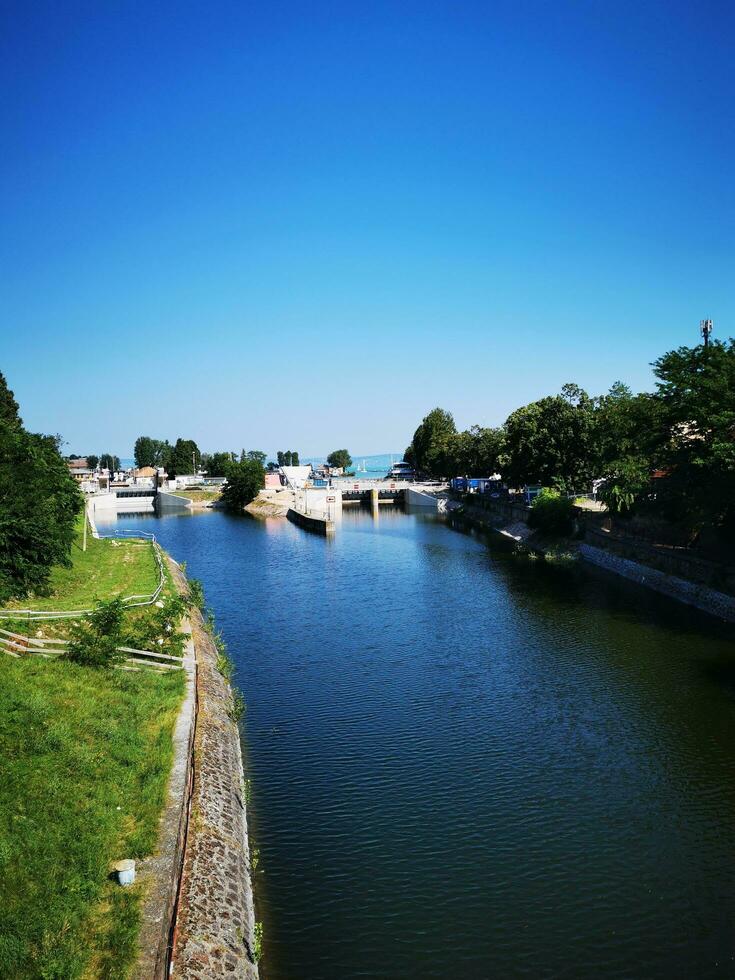 Photo of a picturesque river flowing through a vibrant green countryside