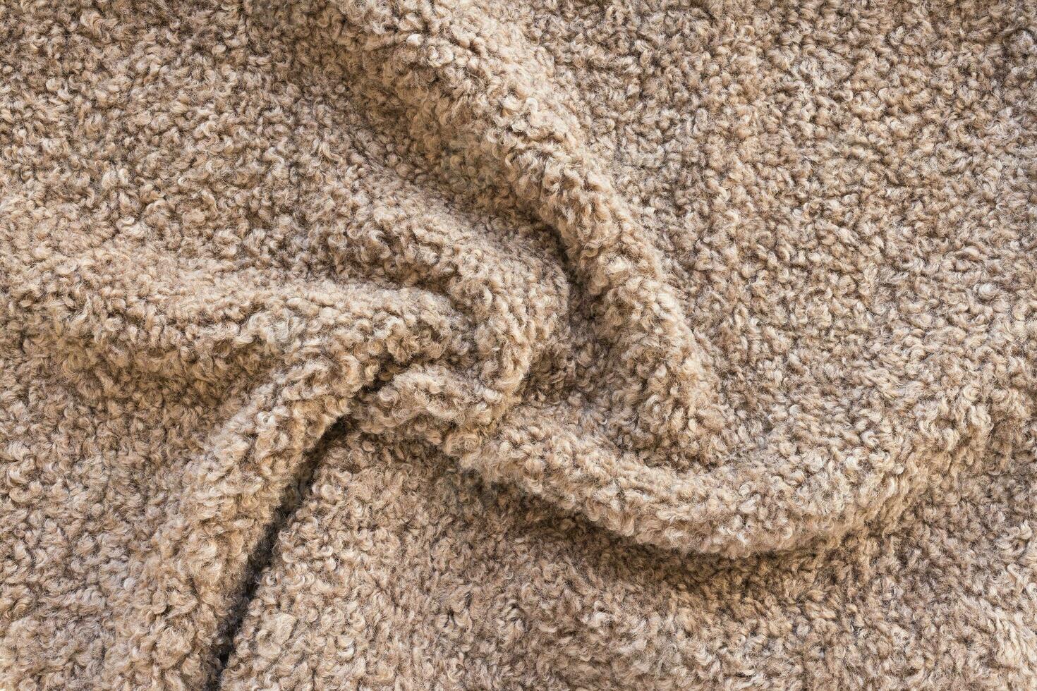New soft brown curly teddy fleece plush throw blanket or pillow case. Abstract fabric texture background with curles. Top view, closeup photo