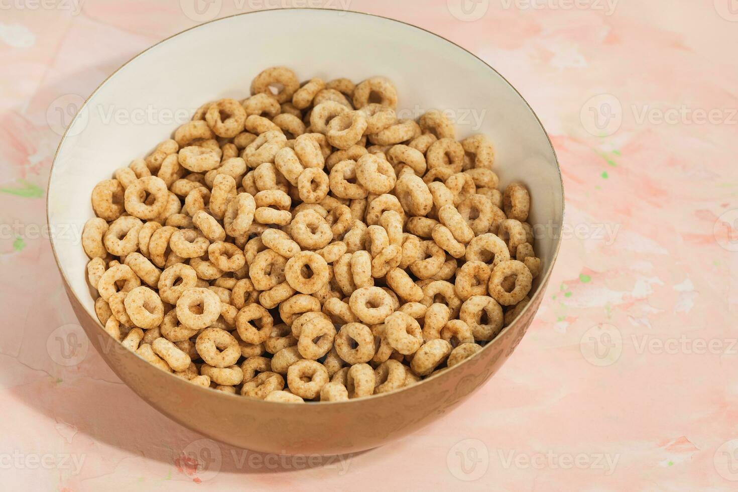 Delicious honey cheerios cereal in a bowl on pink background. Closeup, flat lay, copy space. Breakfast concept photo