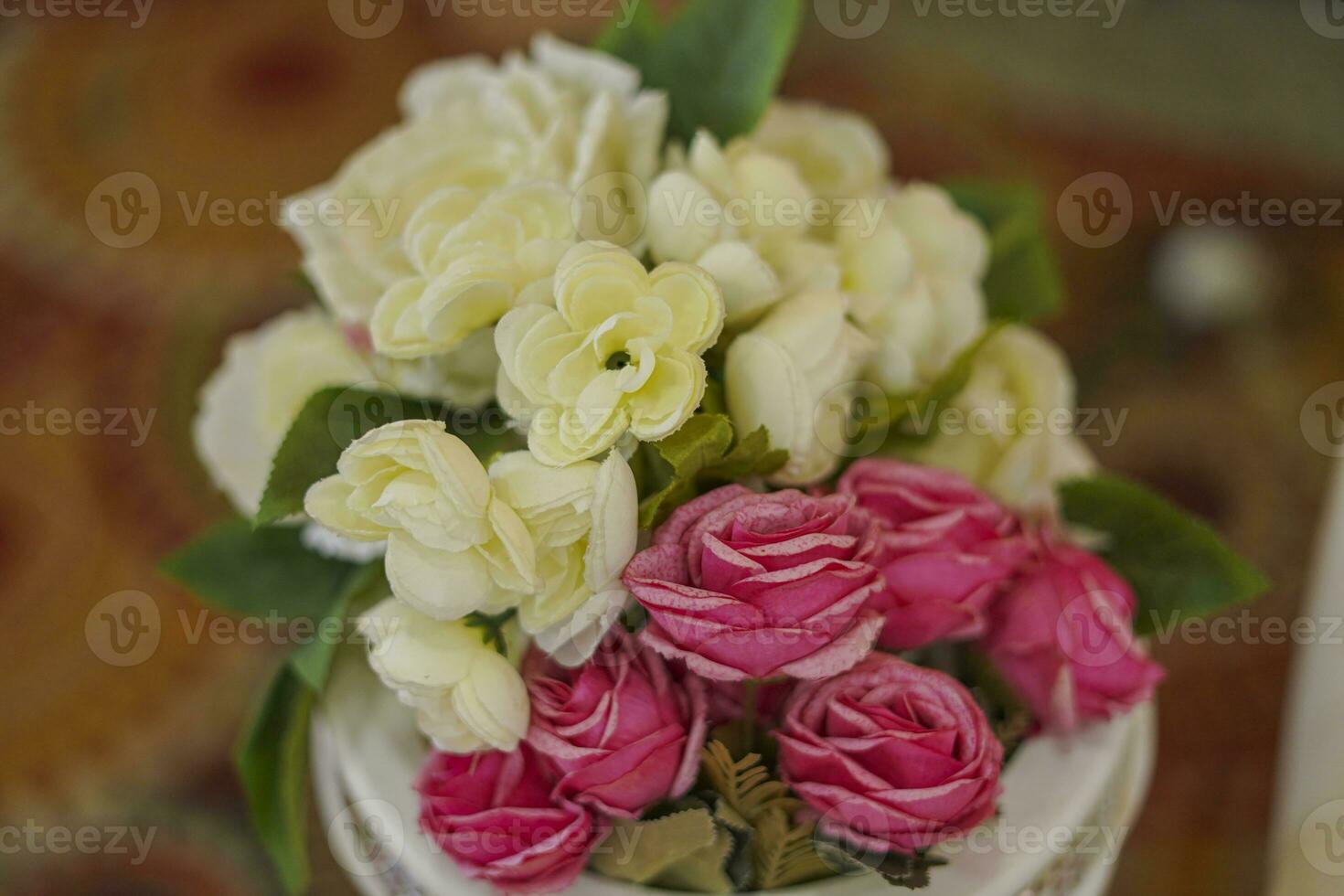 A bouquet of white roses in a cup on a wooden table photo