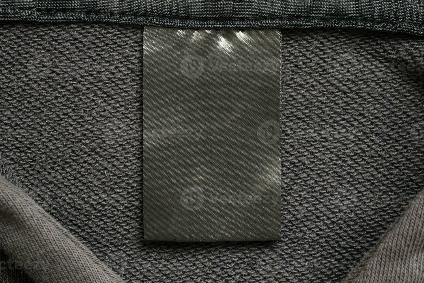 Blank black laundry care clothes label on black fabric texture background photo