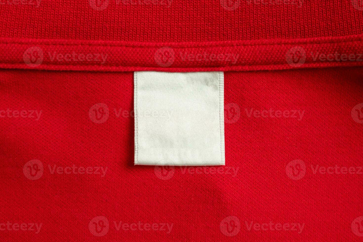 Blank white laundry care clothes label on red shirt fabric texture background photo