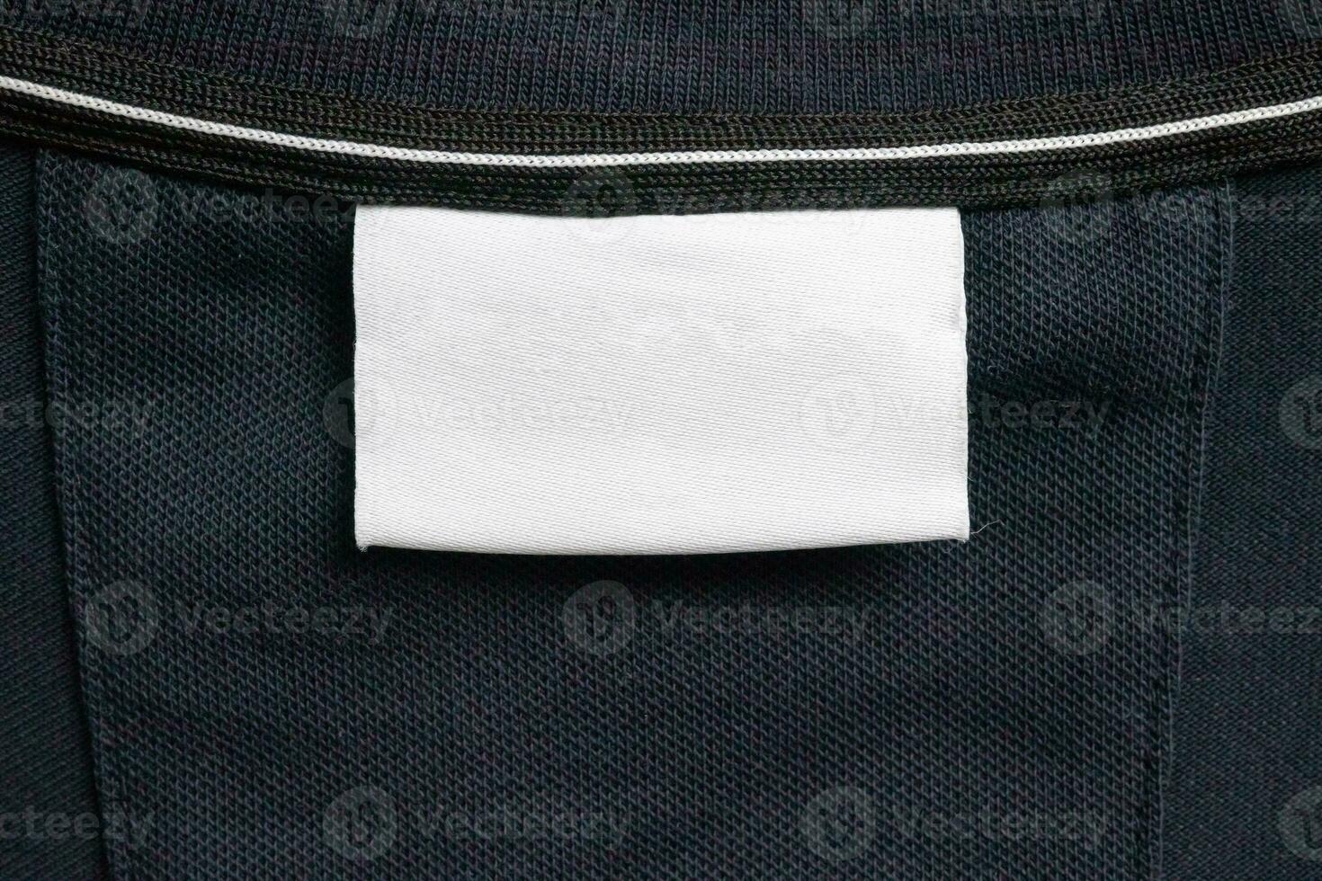 Blank white laundry care clothes label on black shirt fabric texture background photo