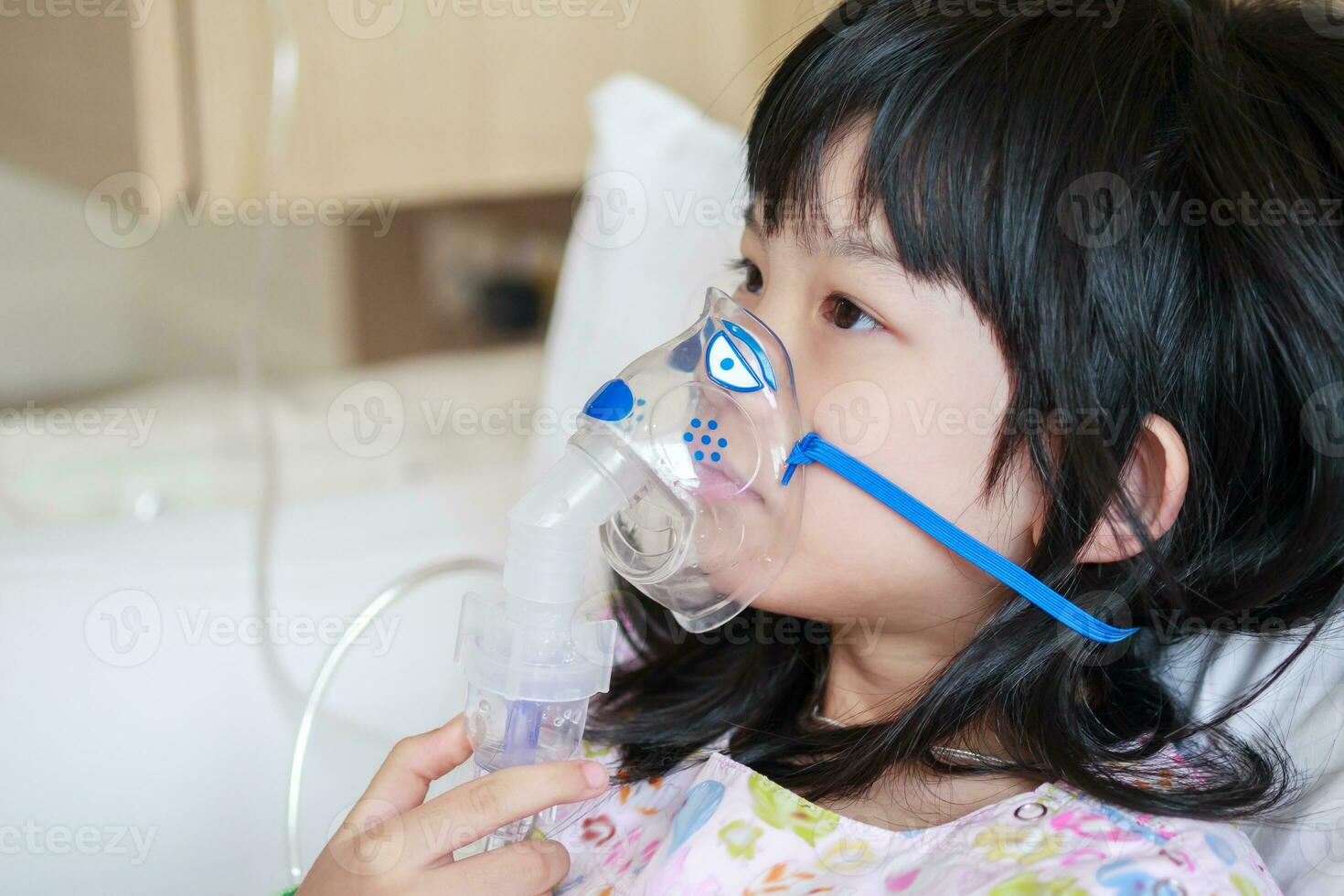 Sick little asian girl inhalation with nebulizer for respiratory treatment photo