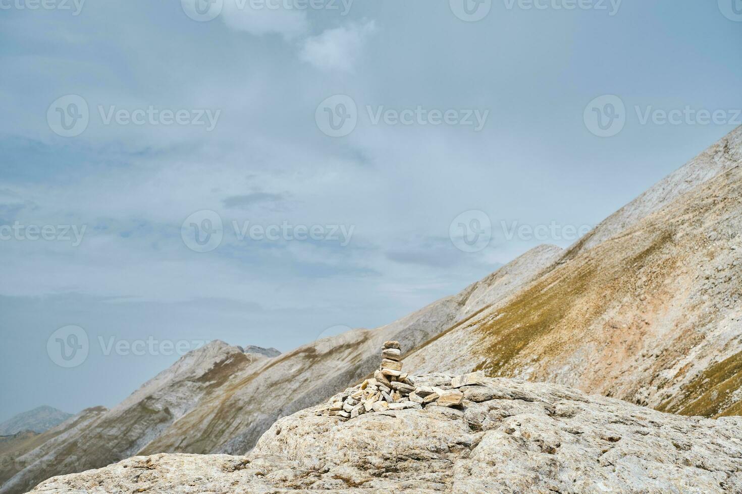 Pyramid of stones on pass in high mountains against background of the sky and the Pirin mountains photo