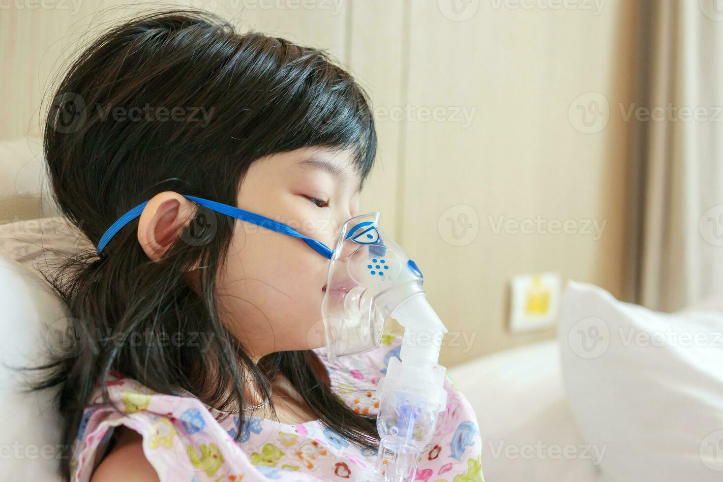 Sick little asian girl inhalation with nebulizer for respiratory treatment photo