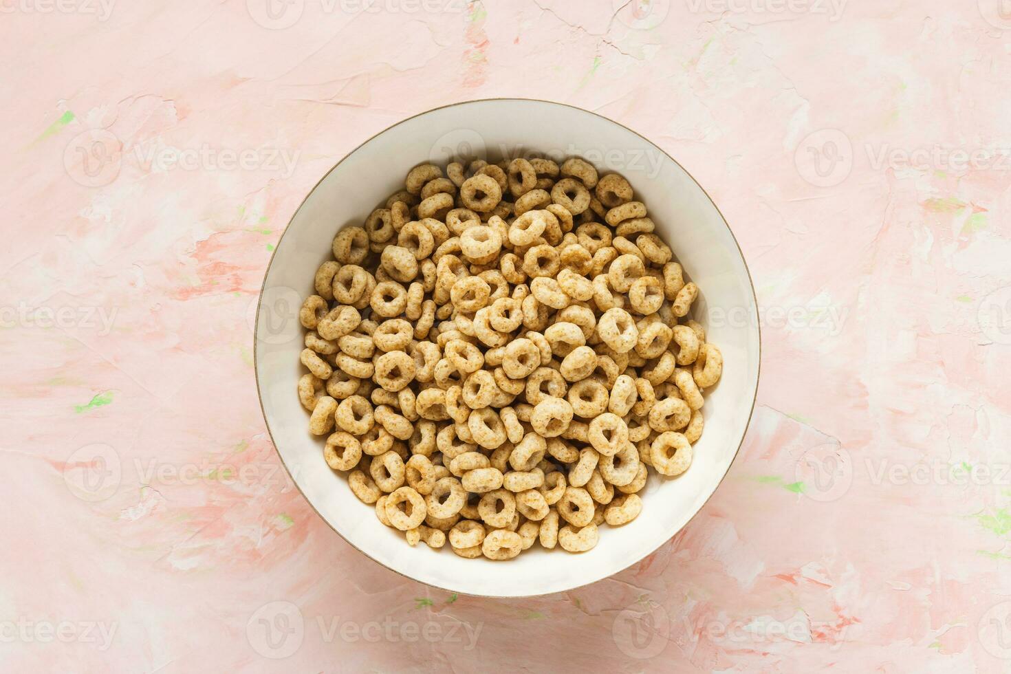 Delicious honey cheerios cereal in a bowl on pink background. Top view, flat lay, copy space. Breakfast concept photo