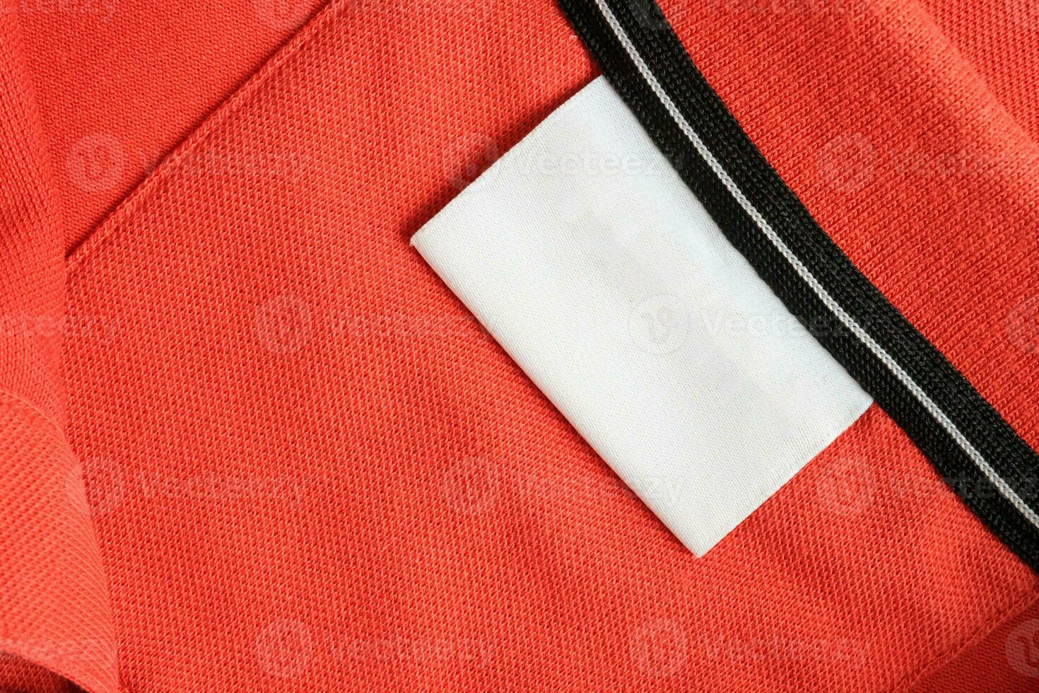 Blank white laundry care clothes label on orange shirt fabric texture background photo