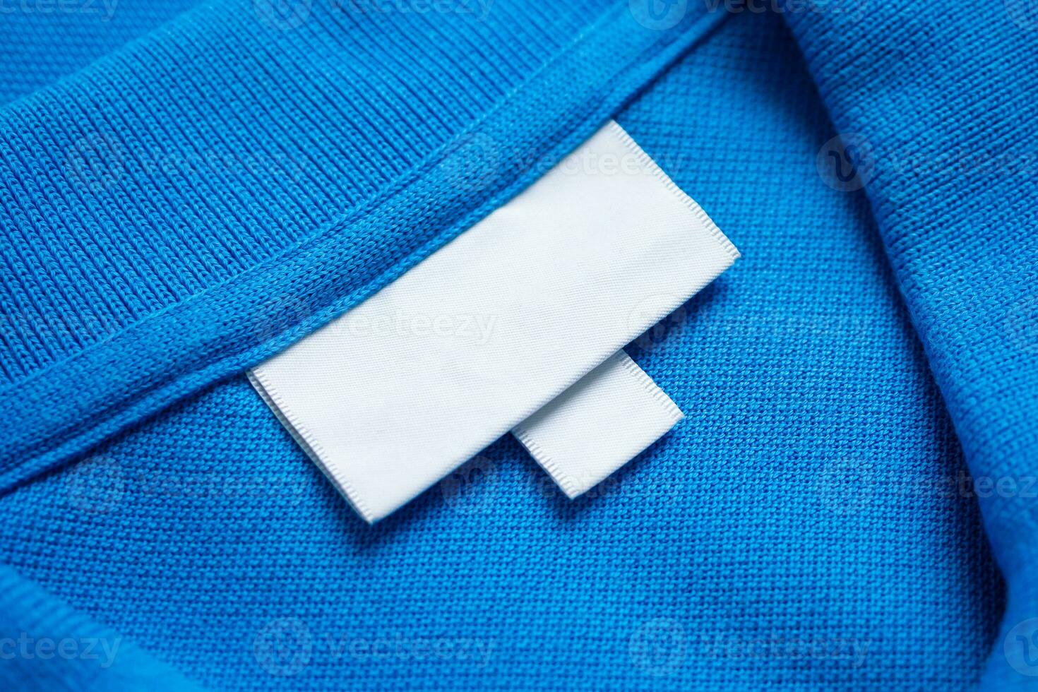 Blank white laundry care clothes label on blue shirt fabric texture background photo