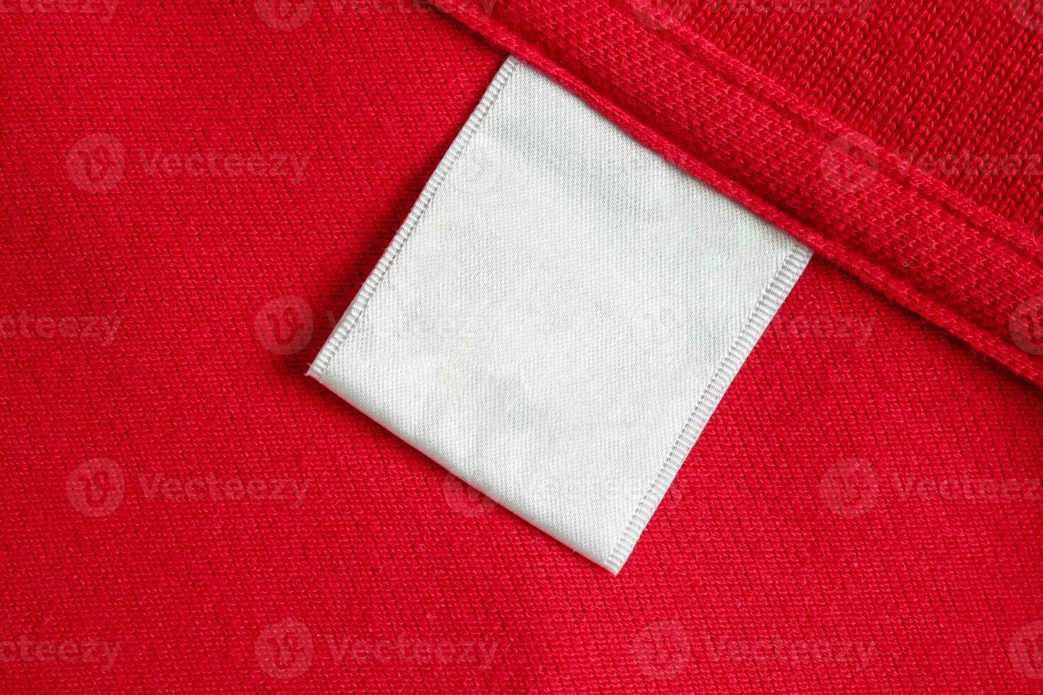 Blank white laundry care clothes label on red shirt fabric texture background photo