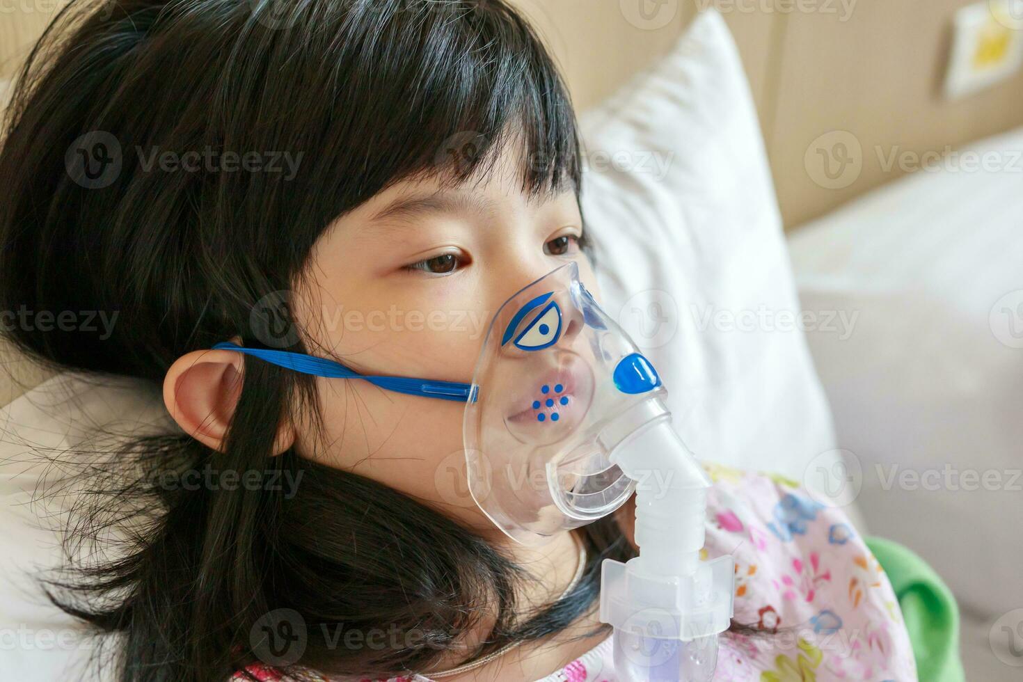 Sick little asian girl inhalation with nebulizer for respiratory treatment photo