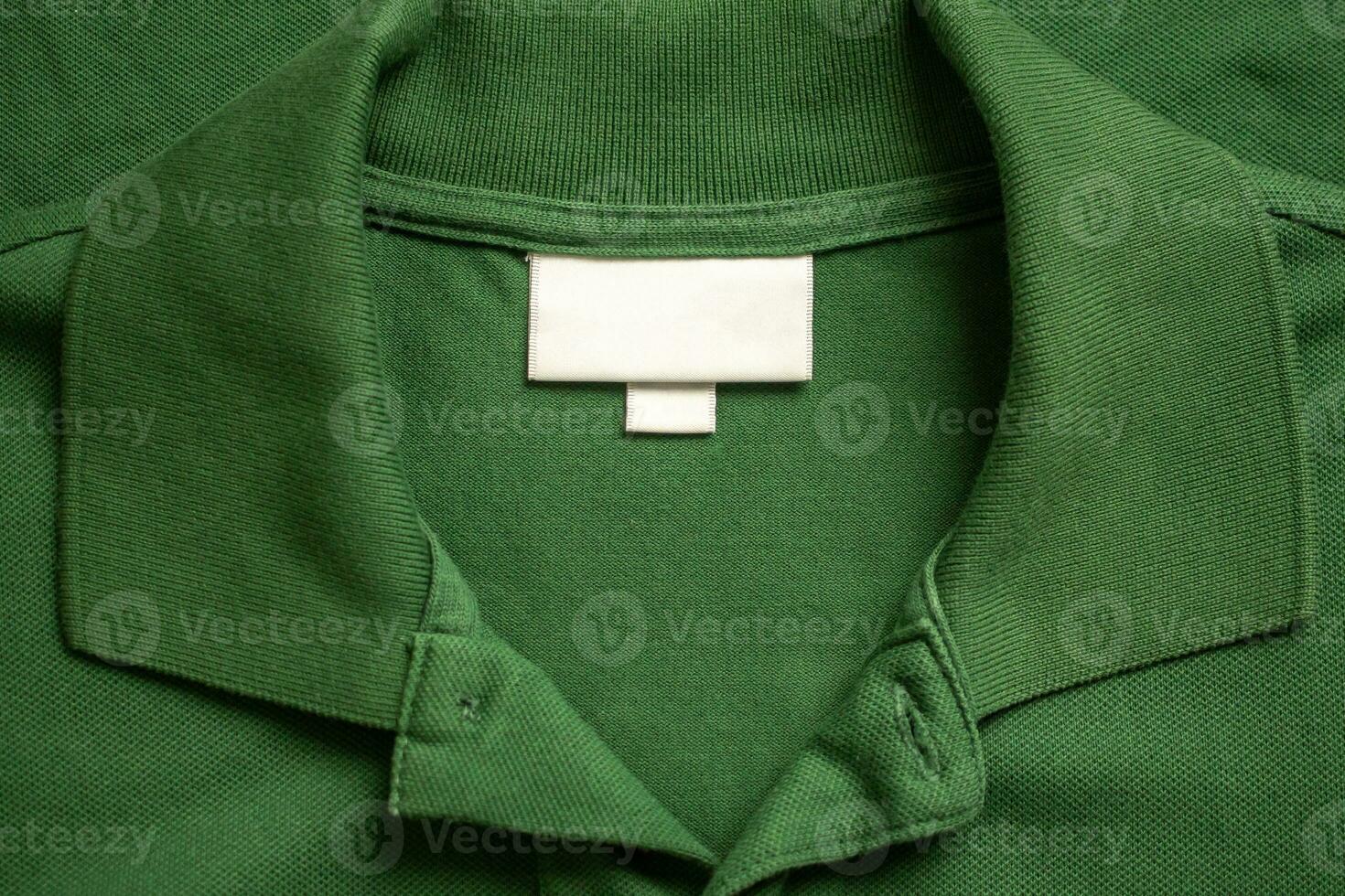 Blank white laundry care clothes label on green shirt fabric texture background photo