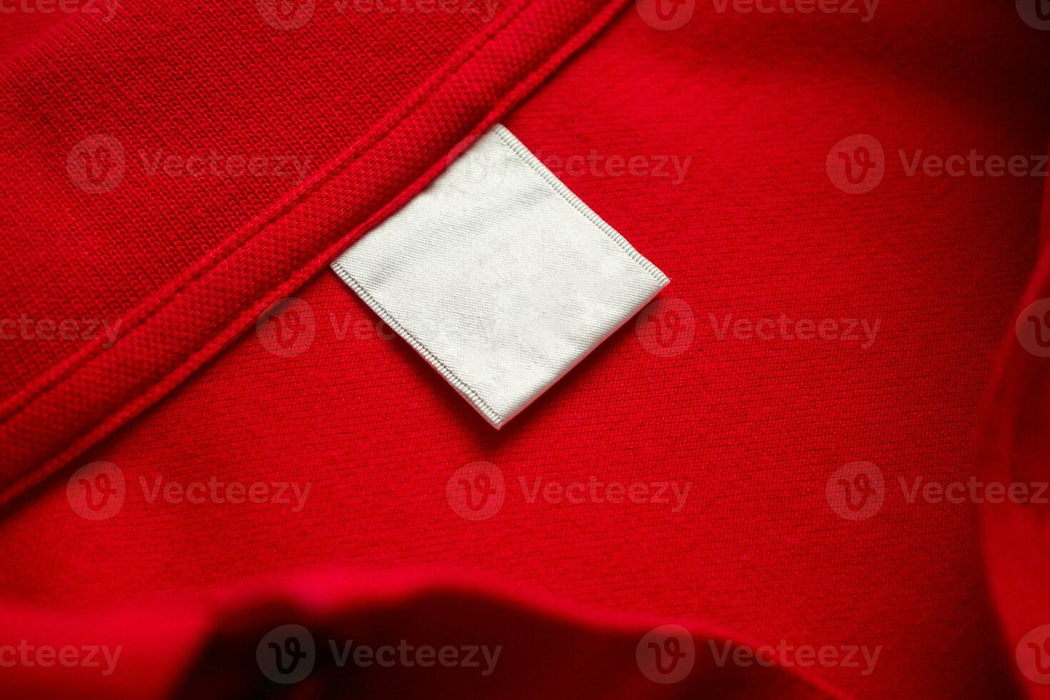 Blank white laundry care clothes label on red shirt fabric texture background photo