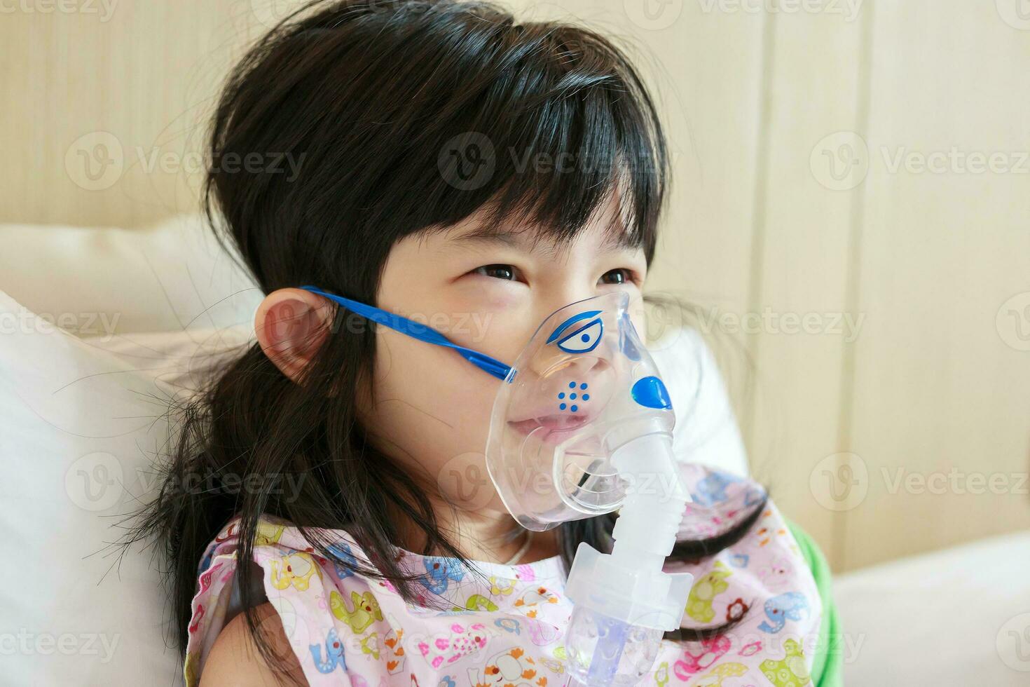 Sick little asian girl inhalation with nebulizer for respiratory treatment photo