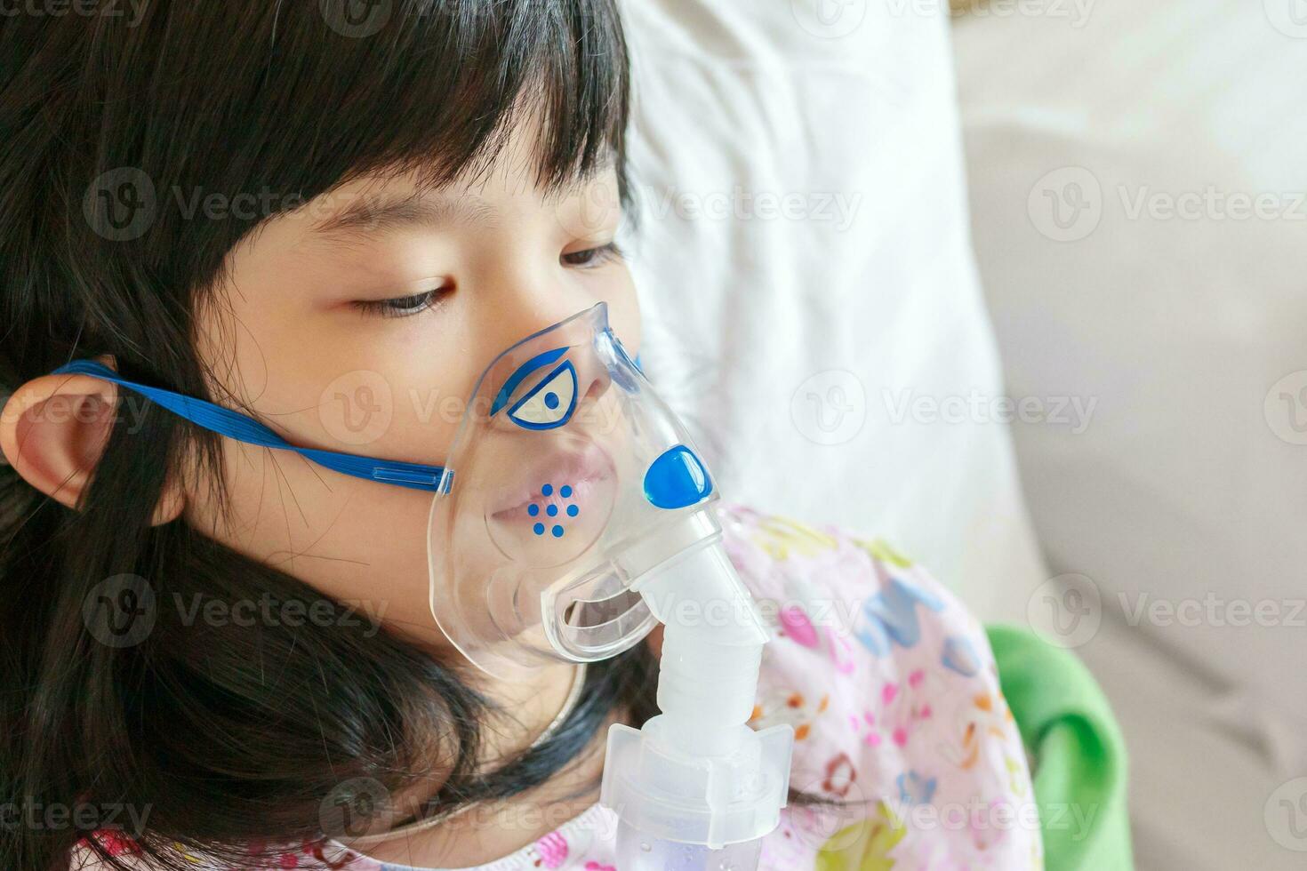 Sick little asian girl inhalation with nebulizer for respiratory treatment photo