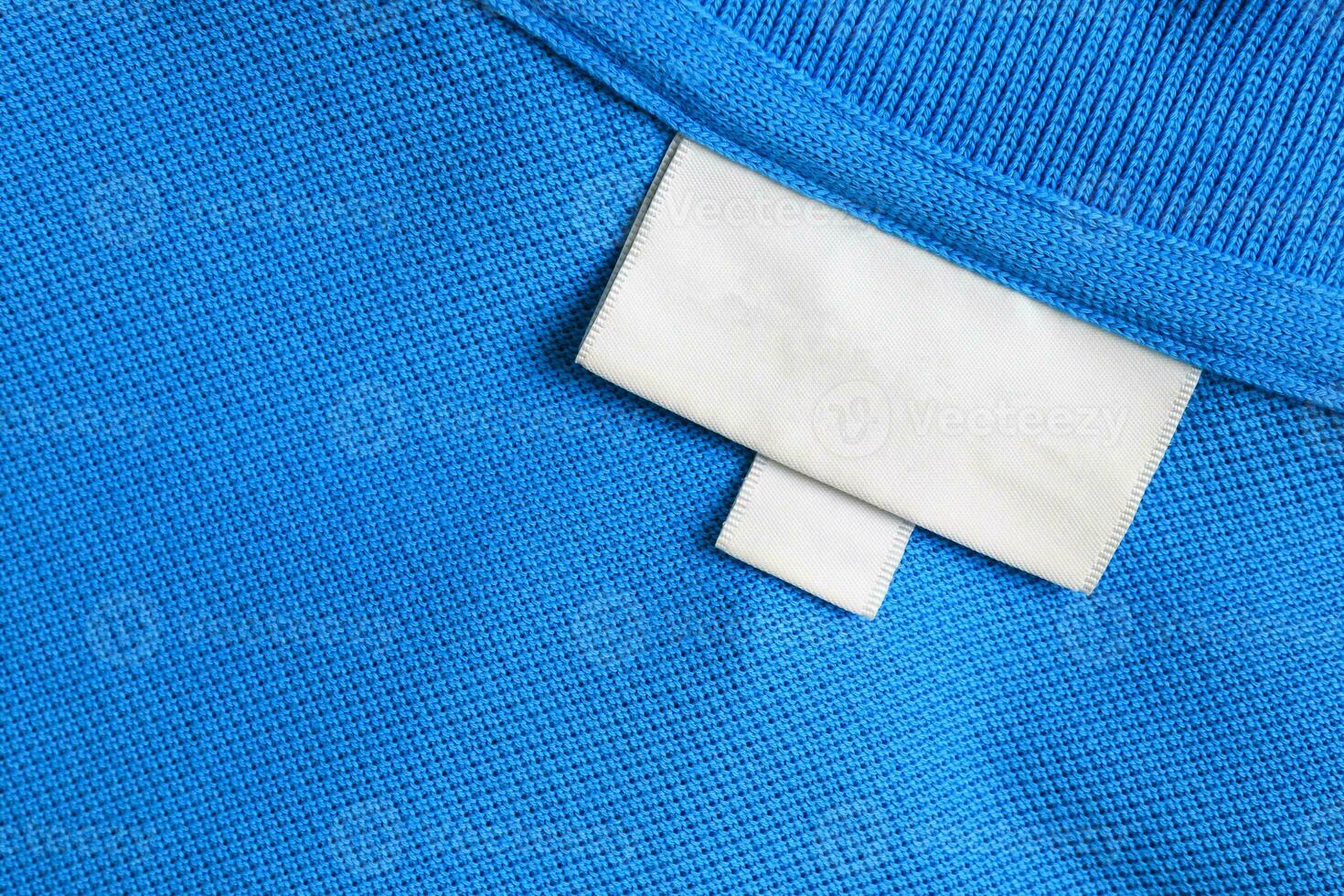 Blank white laundry care clothes label on blue shirt fabric texture background photo