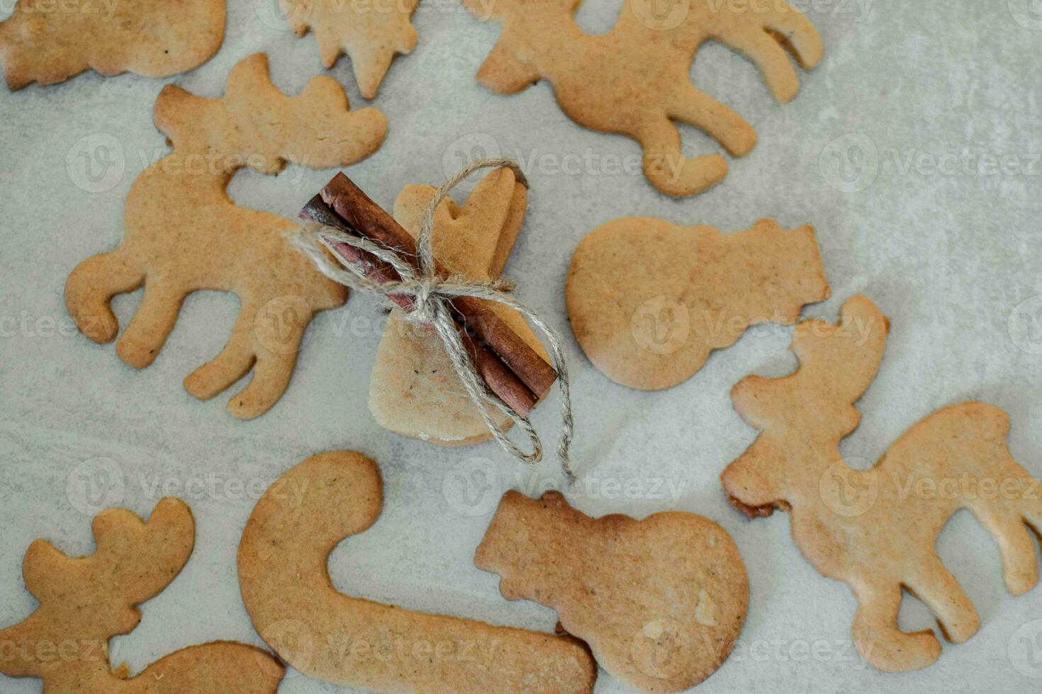 Homemade gingerbread cookies on baking paper are decorated with a cinnamon stick and a bow. photo