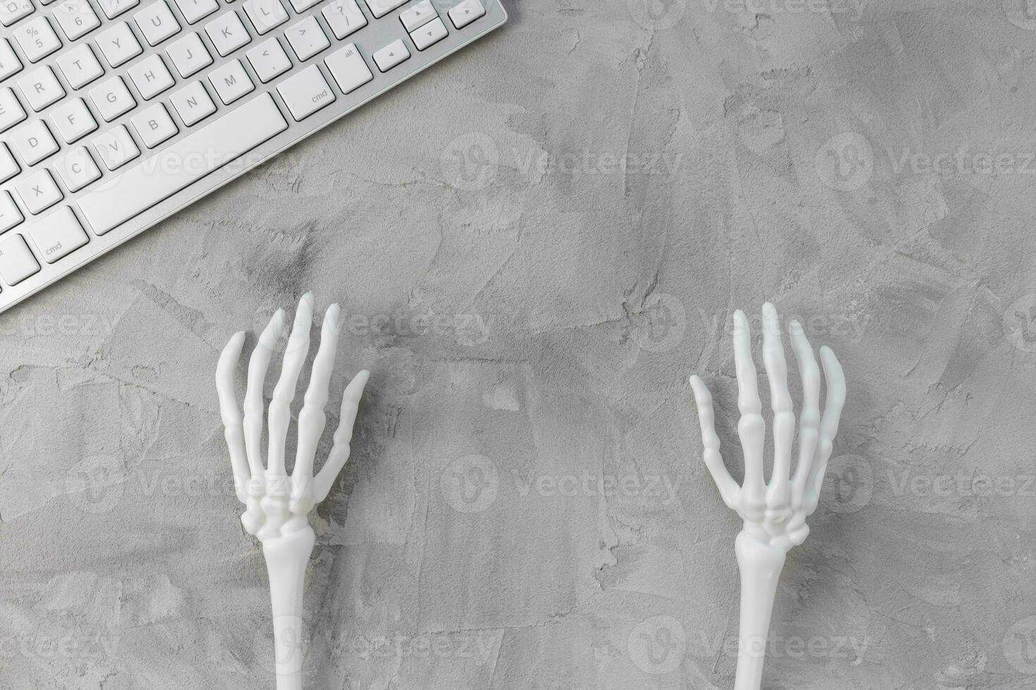Halloween gray background with white skeleton hands and computer keyboard. Halloween holiday online shopping banner mockup. Top view, copy space photo