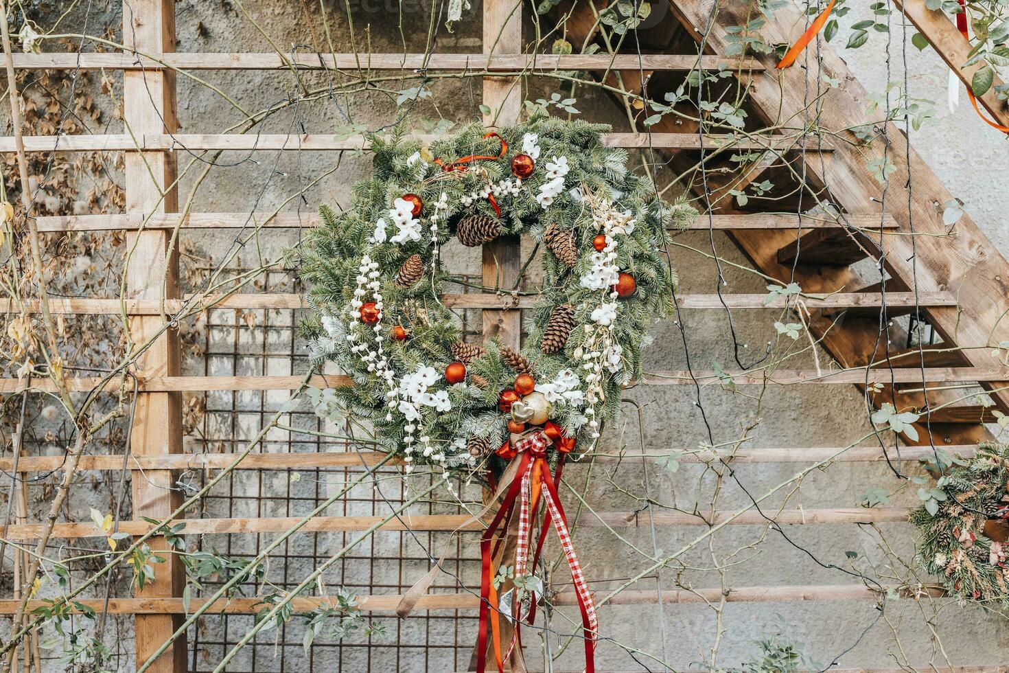 DIY Christmas wreath with pine cones and red decoration on wall photo