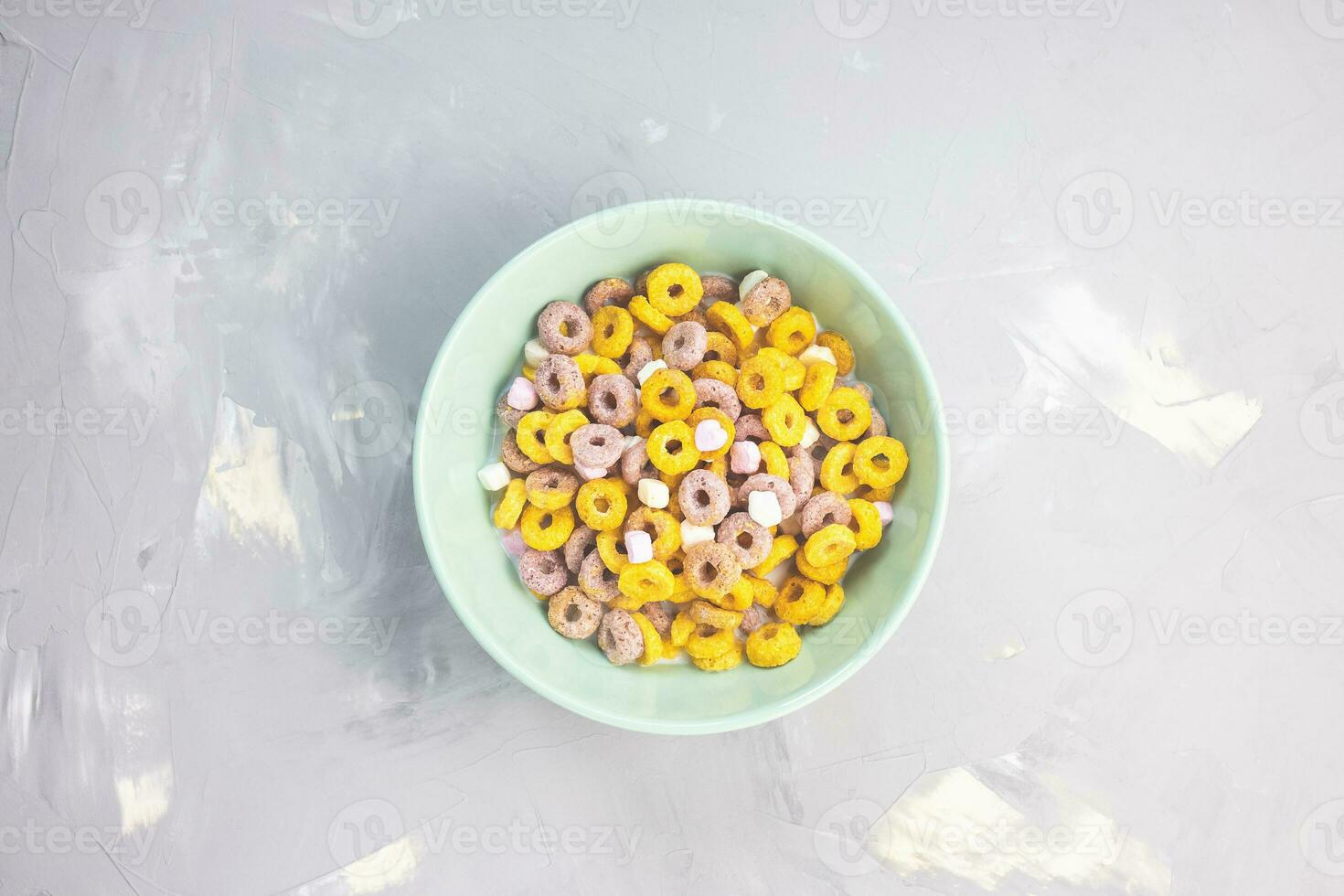 Multi colored cereal fruit loops in a bowl on gray background. Top view, flat lay, copy space. Breakfast concept photo