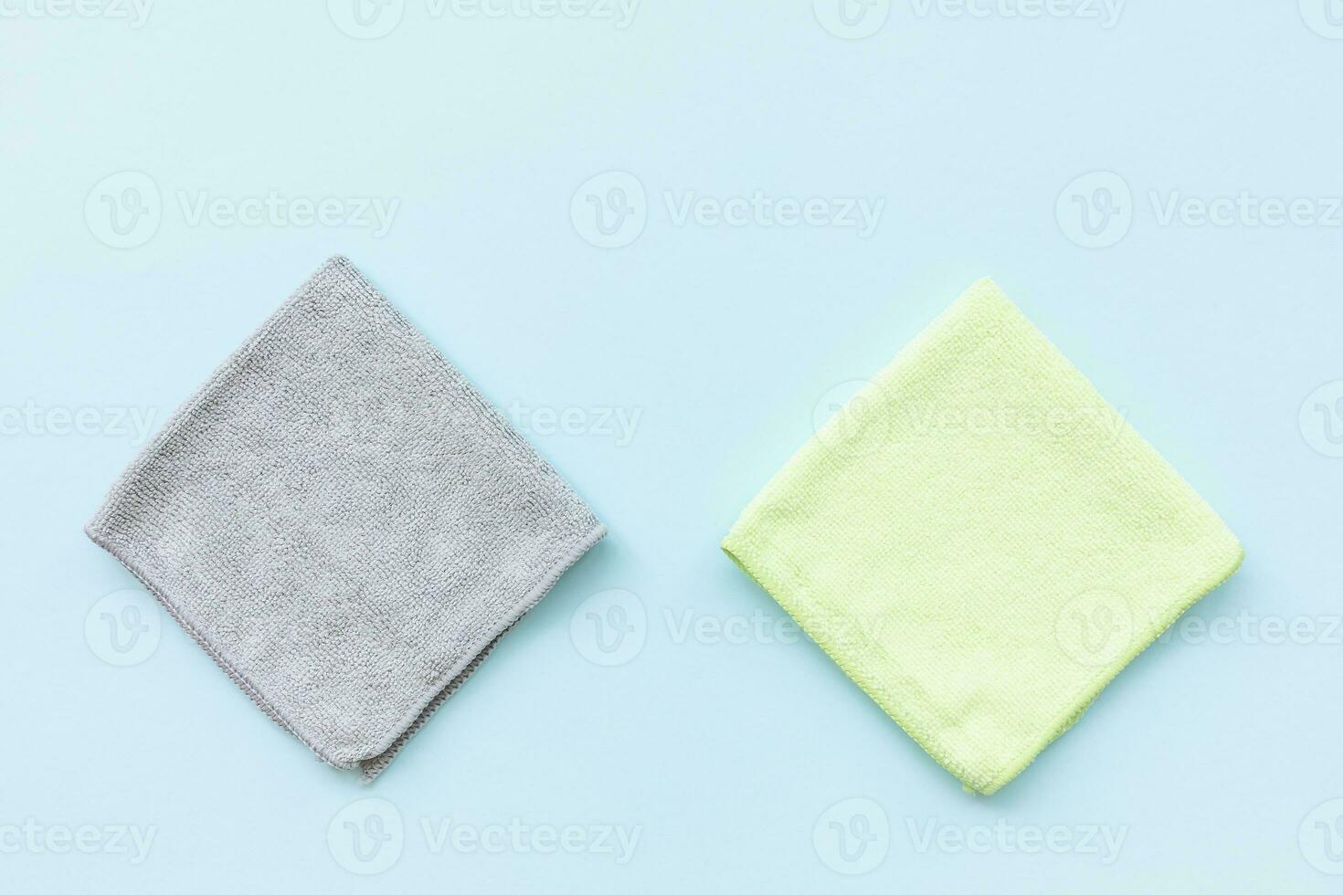 Two new folded microfiber cloth for cleaning on blue background. Cleaning micro fabric towels for dusting and polishing. Domestic household cleaning service concept. Top view, copy space photo