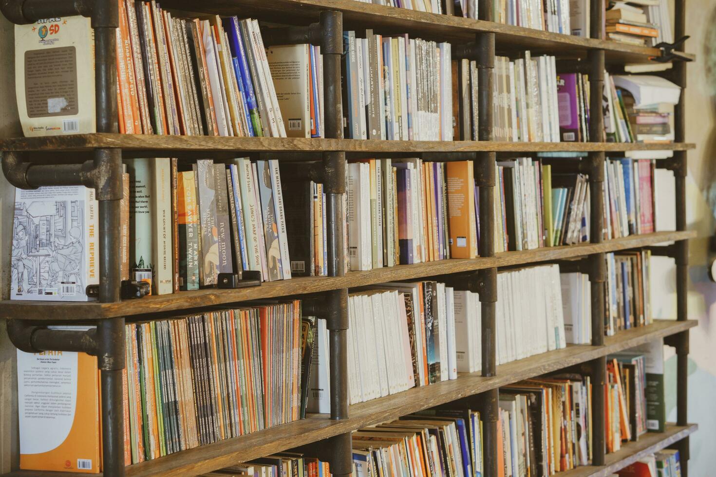 industrial oscuro de madera estantería lleno con social, ficción, yo mejora y biografía libros en un público biblioteca o un librero tienda. yogyakarta, Indonesia - 08 28 2023 foto