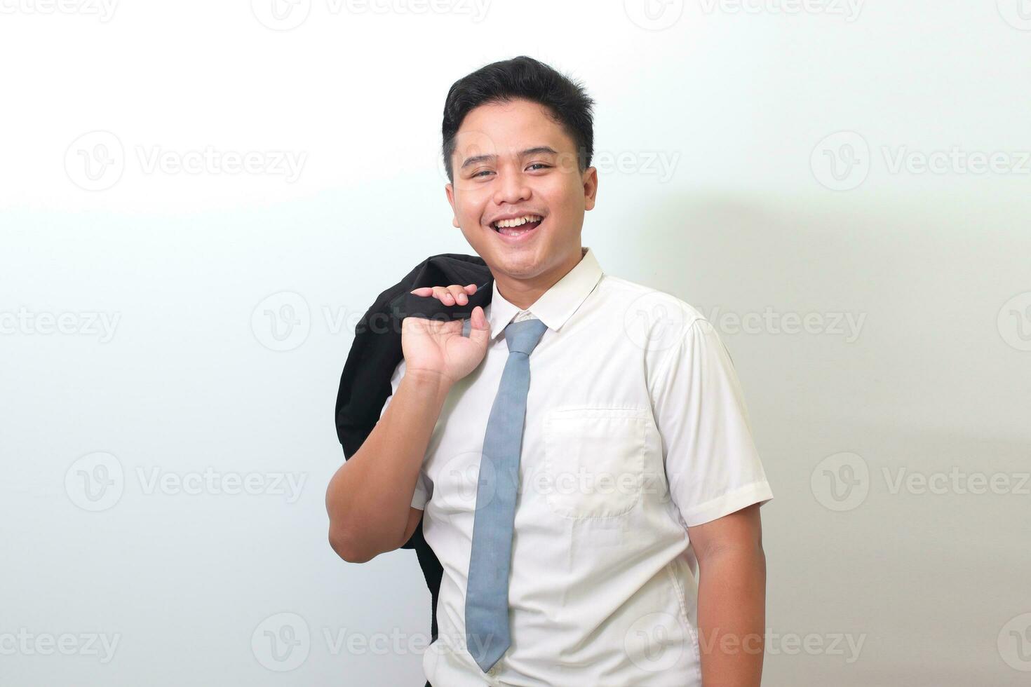 Indonesian senior high school student wearing white shirt uniform with gray tie carrying his backpack on shoulder. Isolated image on white background photo