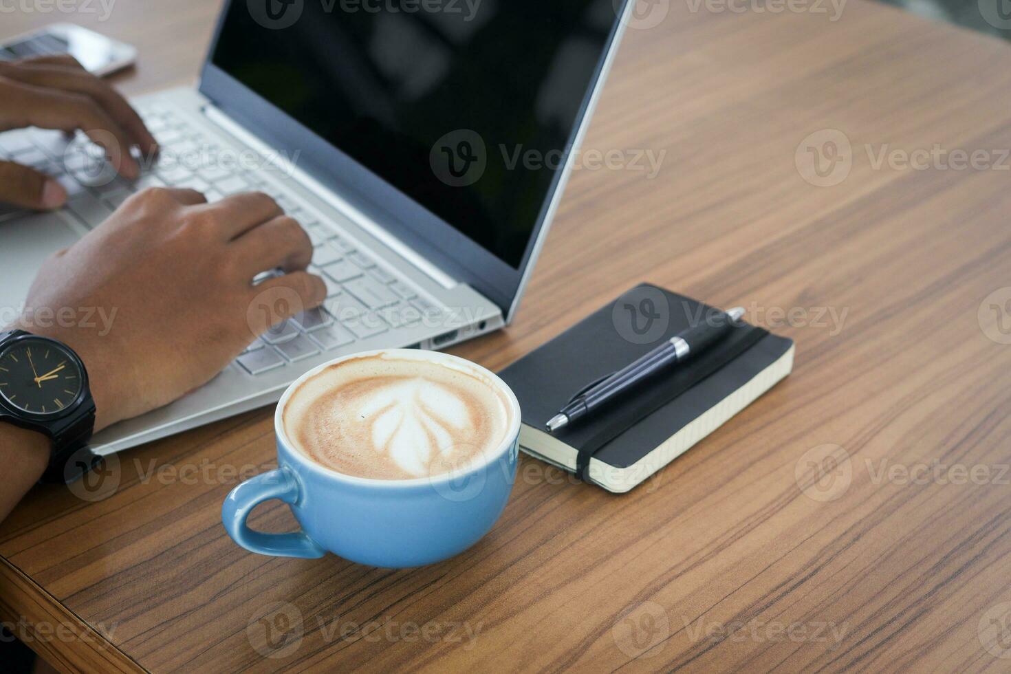 Close up of freelance male hand working on laptop while using a mobile phone. Business and mockup concept photo