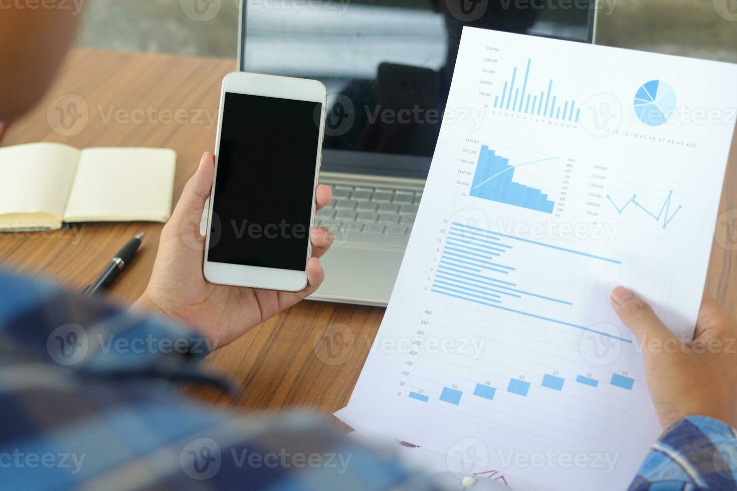 Close up of male freelance worker hand working on laptop and pointing with finger on analysis data with business graph and chart of information diagram on office desk in the morning photo