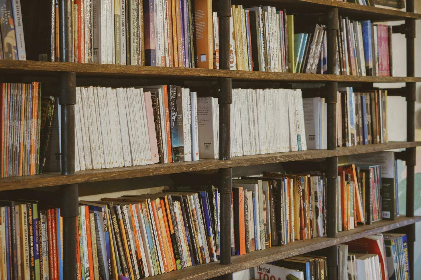 industrial oscuro de madera estantería lleno con social, ficción, yo mejora y biografía libros en un público biblioteca o un librero tienda. yogyakarta, Indonesia - 08 28 2023 foto