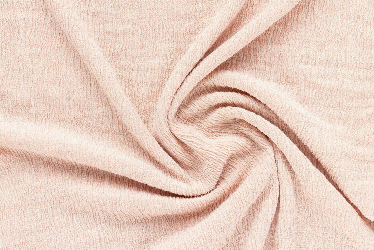 Soft pink fabric with puckered texture twisted in spiral. Abstract background. Fashion and clothes design trends concept photo
