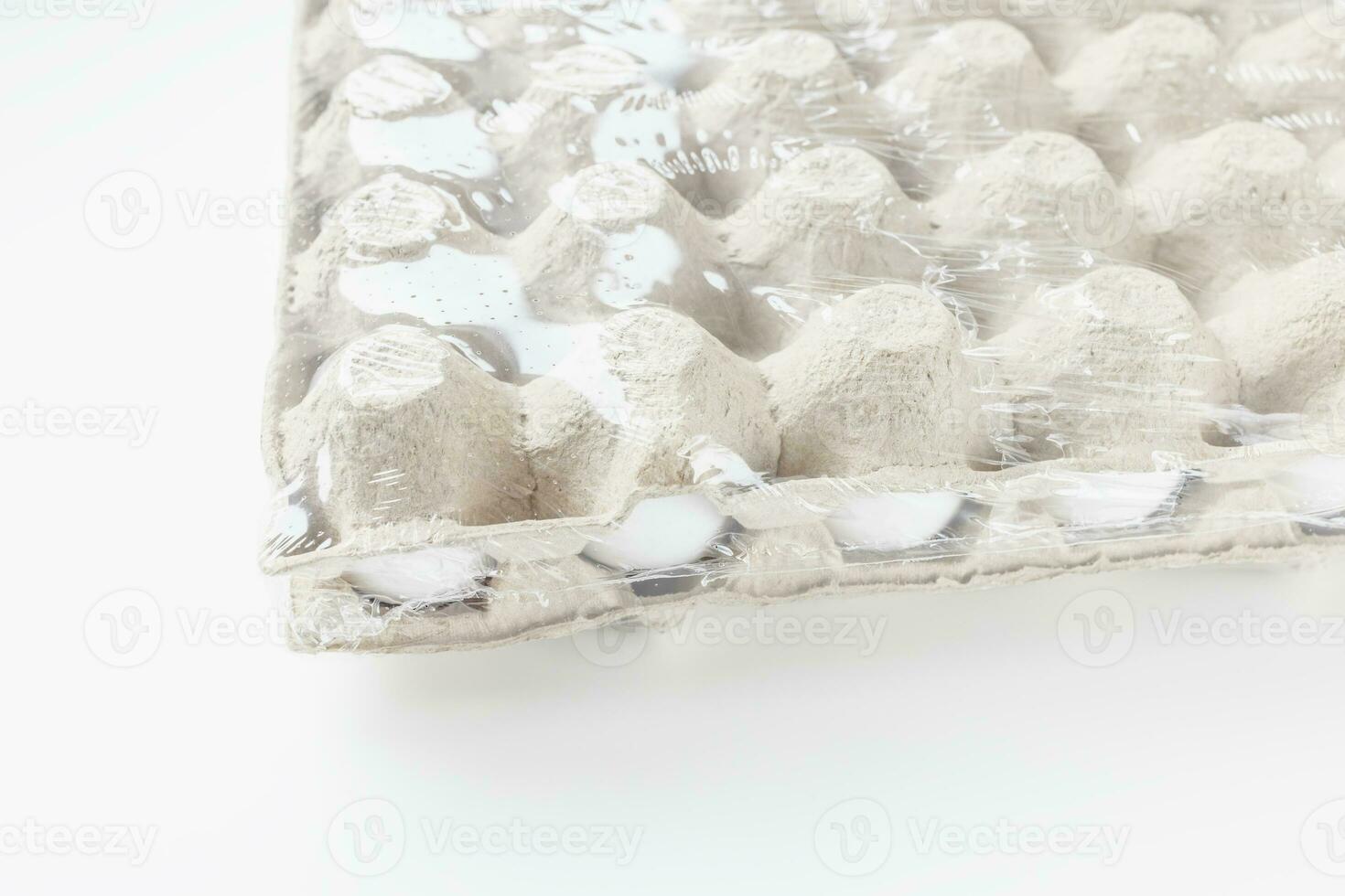Fresh raw 30 pack of large white eggs in cardboard in foil on white background. Consumerism, egg production, organic healthy bio product and Easter holiday concept. Side view, copy space photo