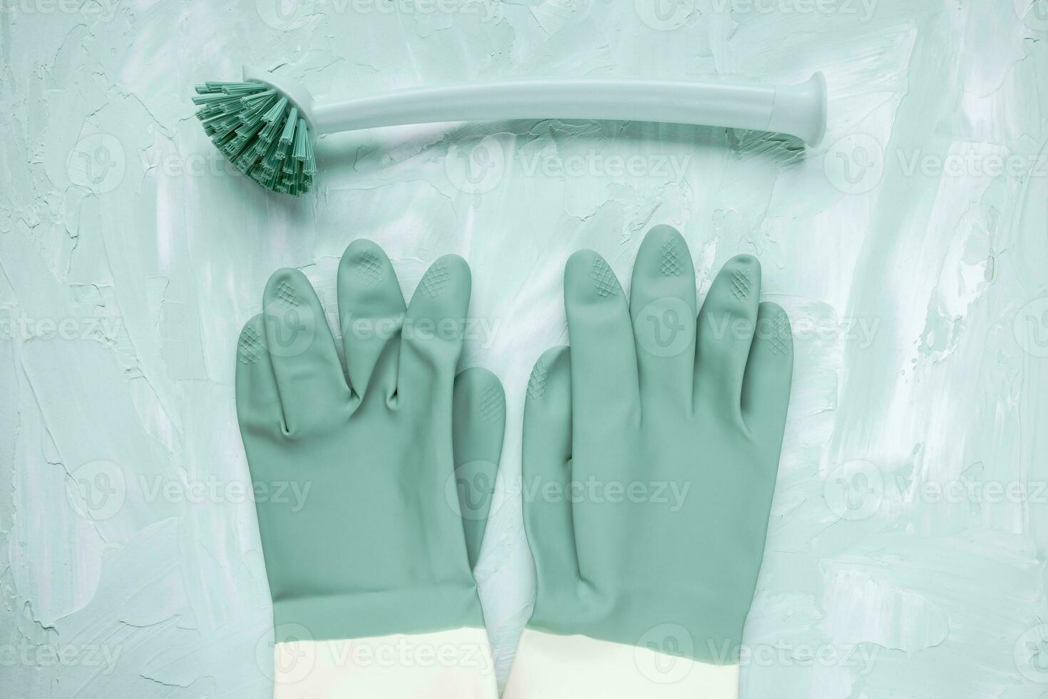 Dish washing brush and gloves on green background photo