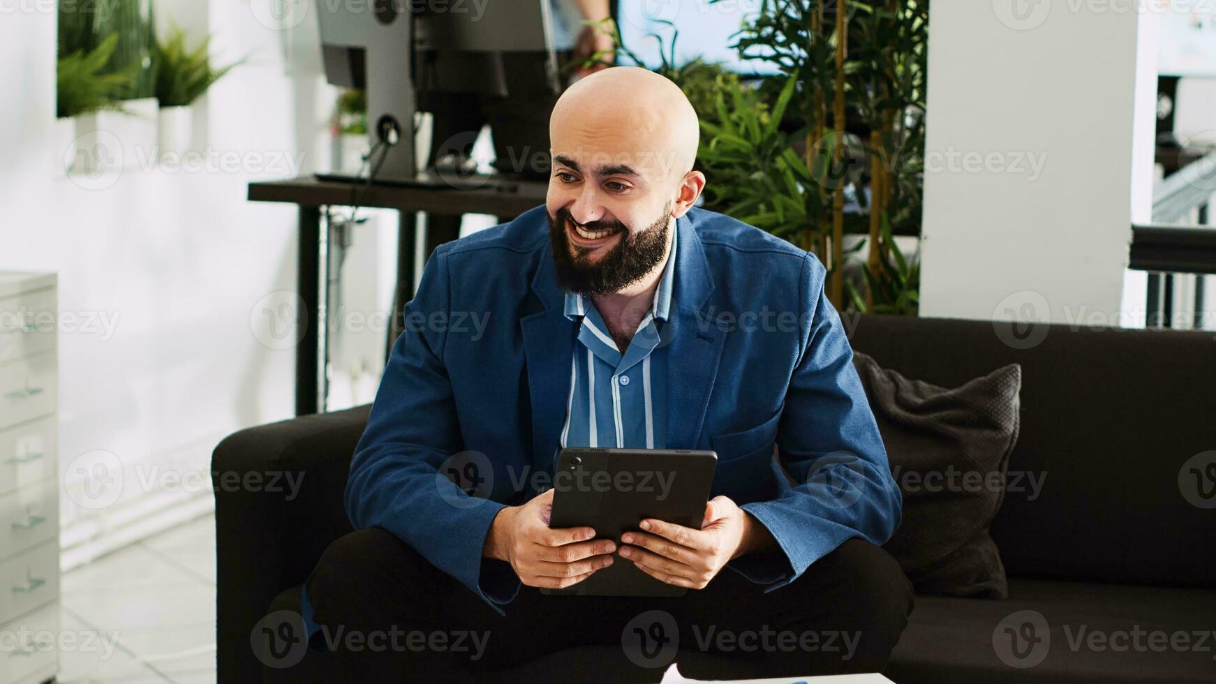 Businessman solving company problems on tablet, looking at online statistics or analytics in open space office. Entrepreneur developing successful software, working on startup plan. Handheld shot. photo