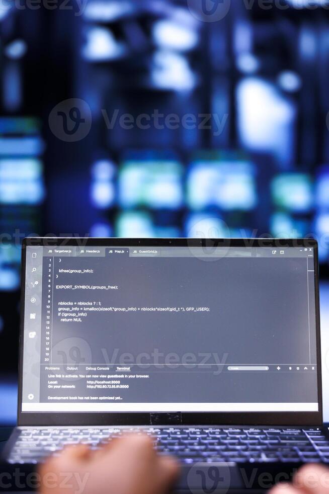 Close up shot of developers updating server rigs, writing complex binary code scripts on laptop. Programmers using JavaScript, Java, and database programming to fortify cybersecurity in data center photo