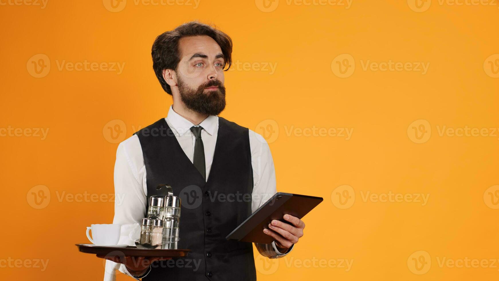 Expert staff member prepares check on tablet while serving in five star restaurant and offer outstanding refined service. Platter with cutlery and modern digital gadget are handled by butler. photo