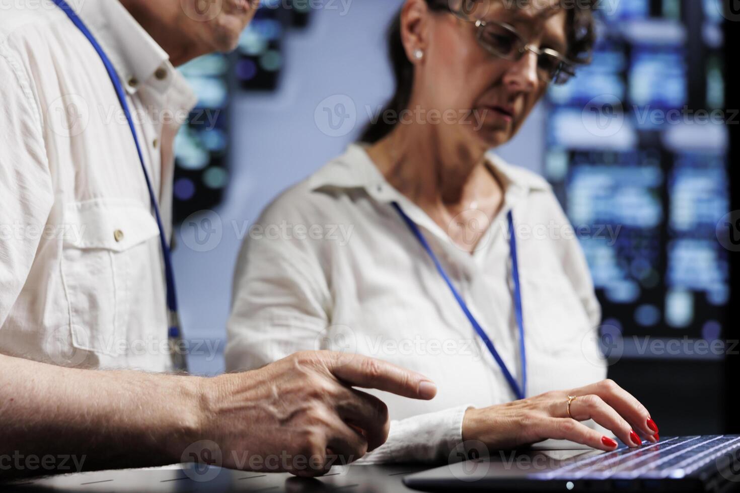 Elderly technical support consultants working to maintain uptime in high tech place. Skilled specialists brainstorming solutions to data center server racks crashing, trying to fix components photo