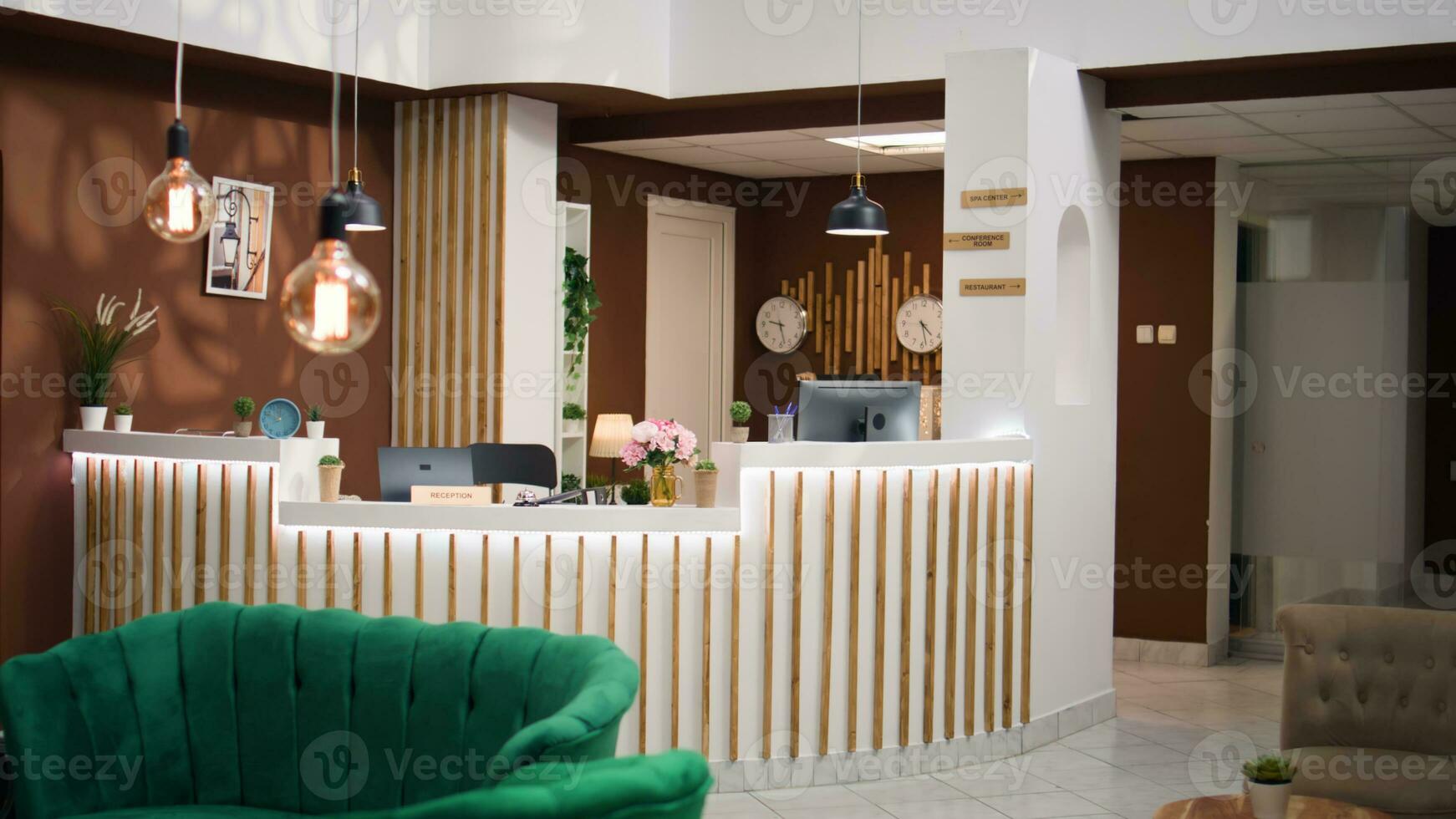 Interior of welcoming rustic hospitality industry hotel lobby filled with plants, waiting for guests. Empty luxurious resort front desk decorated with international timezones on clocks. photo