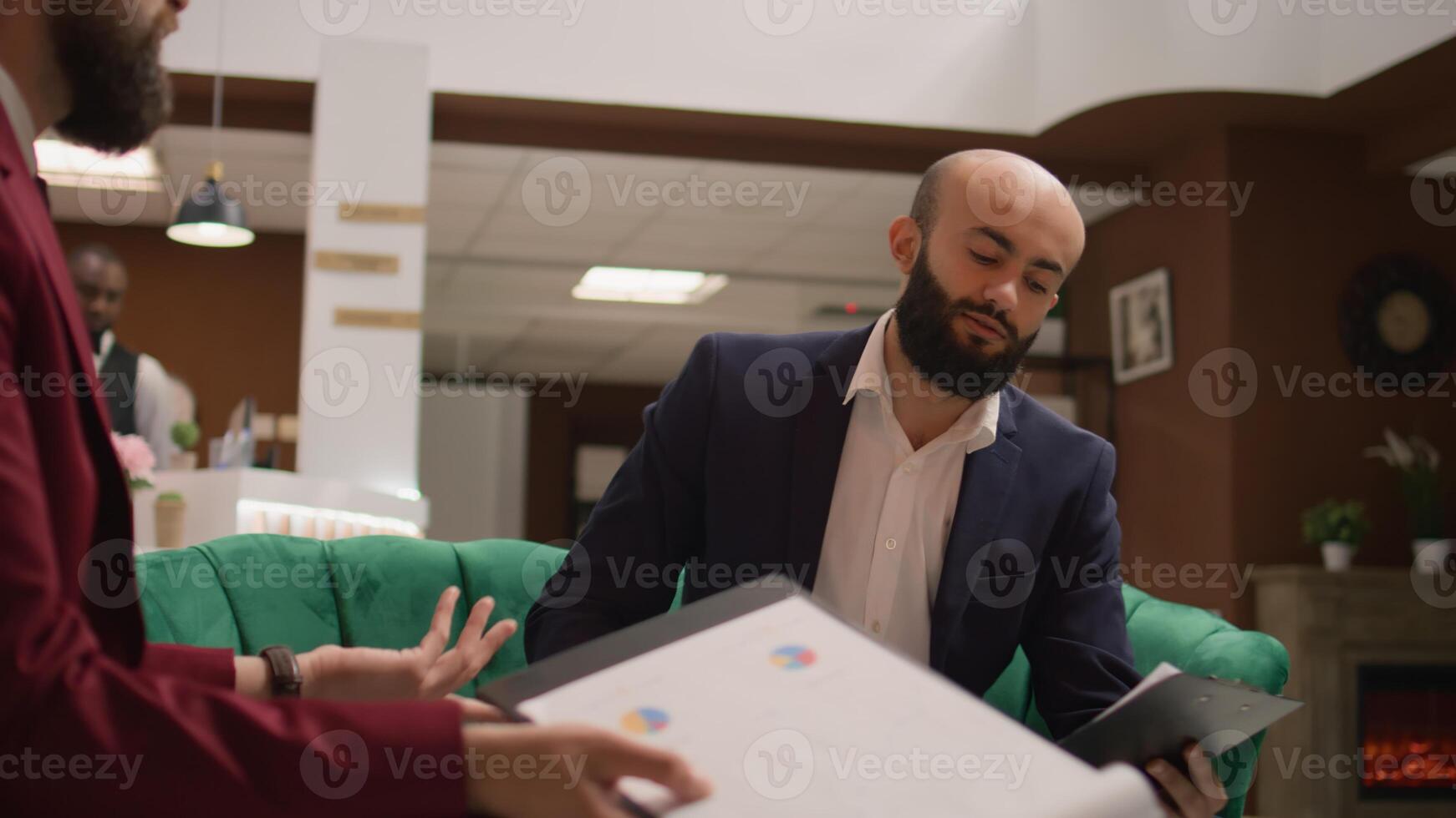 During global business gathering, managerial director proposes revolutionary input. Businessmen dressed properly acting with commitment, reviewing data on papers at hotel reception. photo