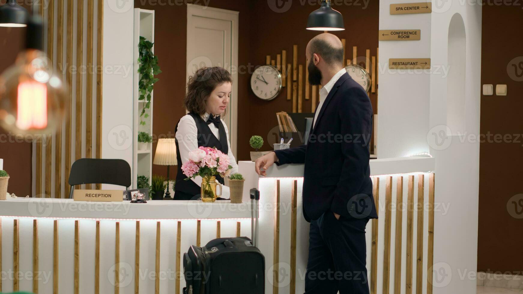 Concierge presenting hotel services to important guest with room reservation due to international conference attendance. Reception staff helping client to ensure pleasant business trip. photo
