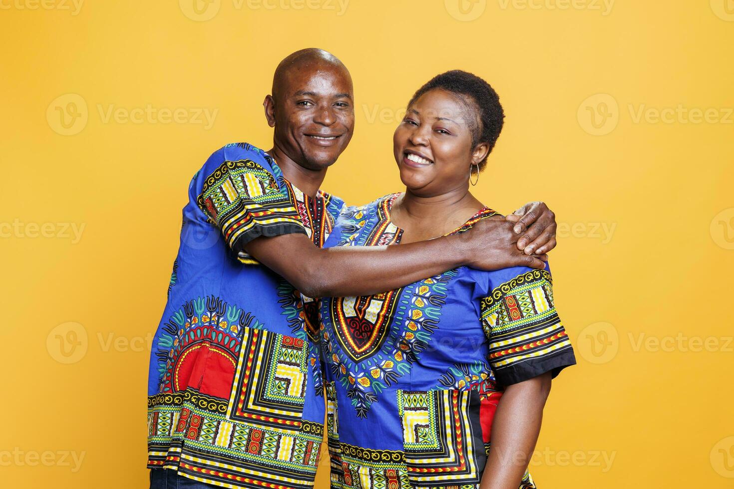 Happy black romantic couple wearing ethnic clothes hugging, showing affection and bonding portrait. Smiling man and woman spouse embracing while posing together and looking at camera photo