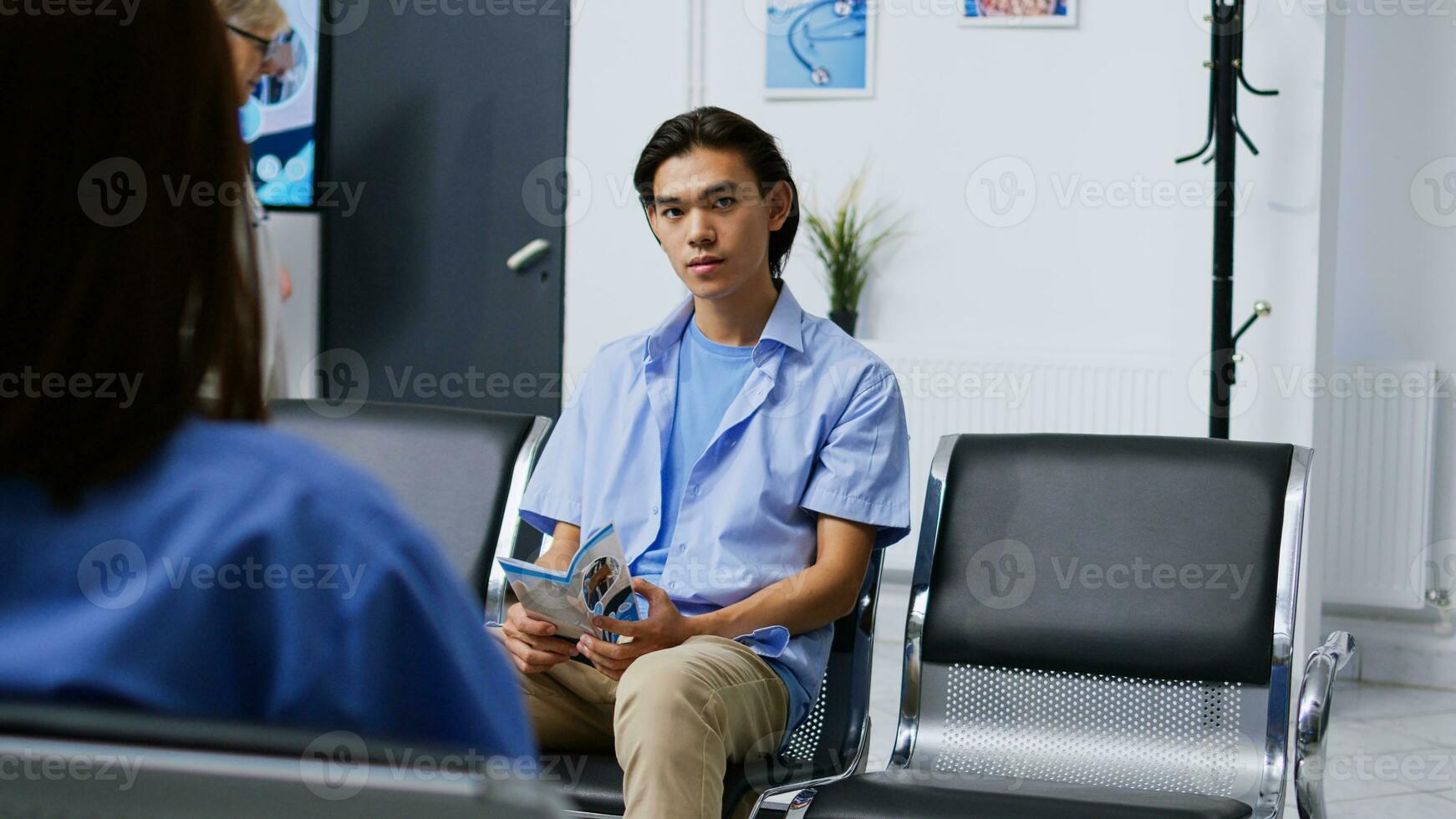 Portrait of asian patient waiting to attend checkup visit with physician, sitting in hospital reception. Man with illness preparing for examination during checkup visit consultation. Medicine concept photo