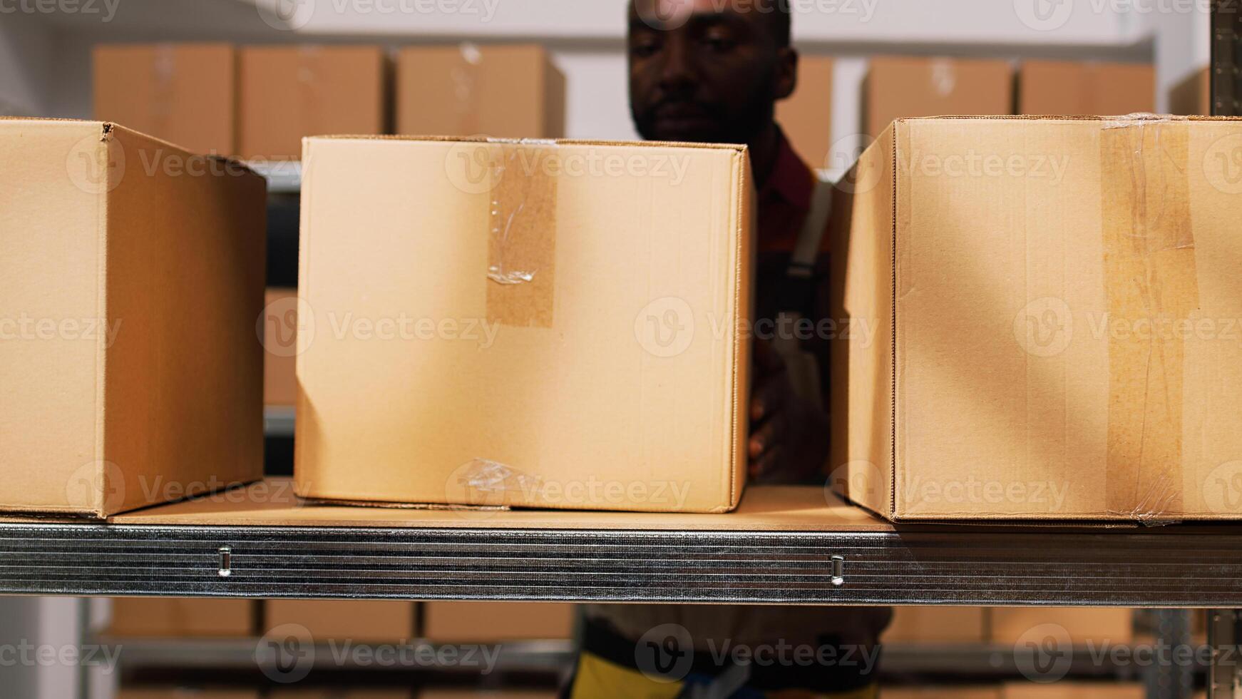 Storehouse manager sorting boxes on rack, organizing merchandise cargo on shelves. Smiling person carrying packages of retail store products in storage room warehouse. Tripod shot. photo