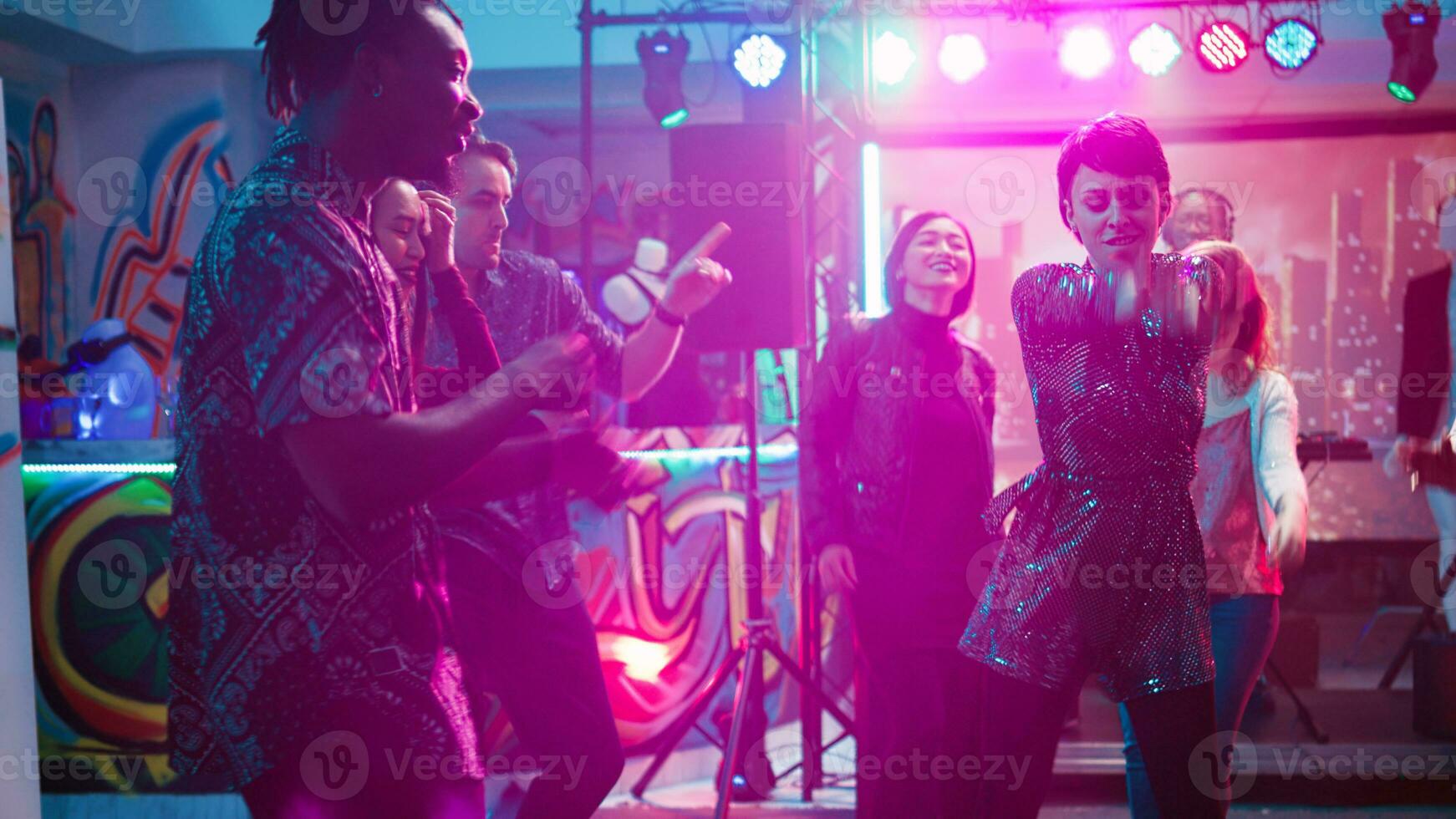 grupo de personas disfrutando disco fiesta, bailando en club música a social reunión. joven hombres y mujer demostración danza se mueve en danza piso, ir de fiesta con etapa luces. Mano disparo. foto