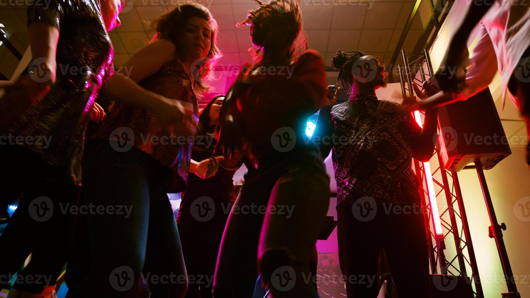 POV of friends dancing at disco party, enjoying social gathering with modern clubbing music on dance floor. Group of people having fun together at dance event in discotheque. Handheld shot. photo