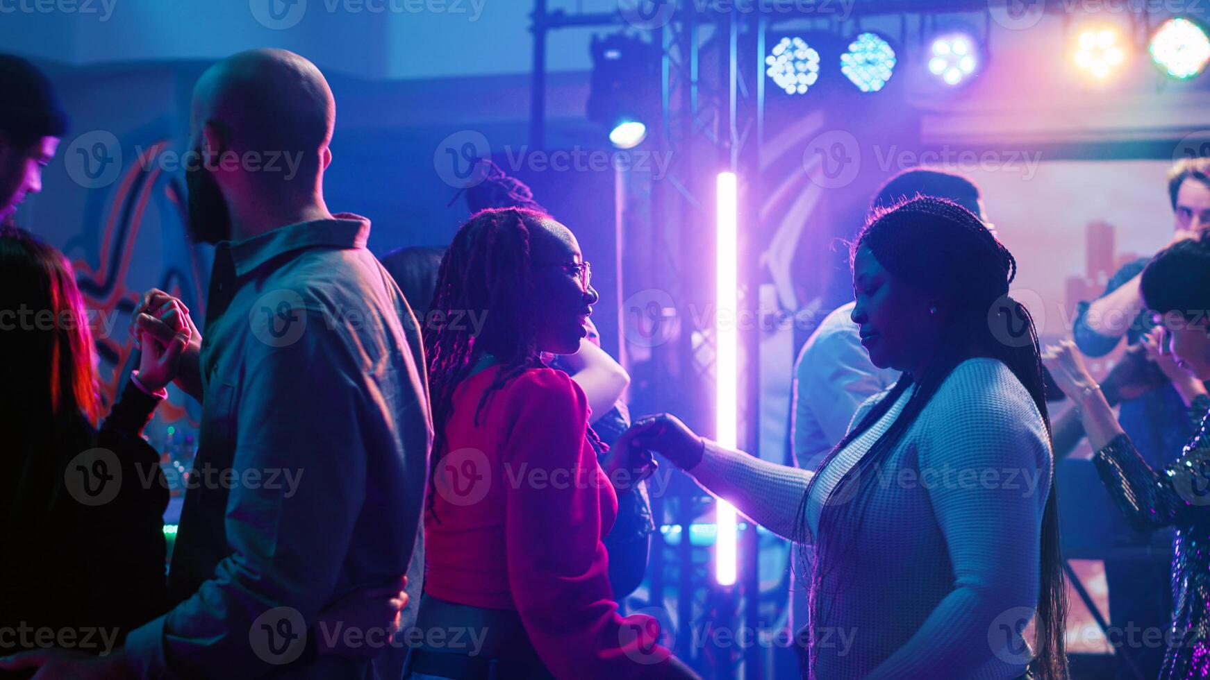 Young couples waltzing at nightclub, dancing in pairs on slow music on dance floor. Happy romantic partners enjoying waltz at discotheque, having fun with spotlights and alcohol. Partying. photo