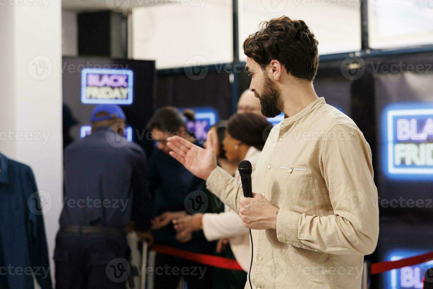 Event host holding microphone announces start of Black Friday sale in modern shopping mall. Retail store owner opening clothing store during seasonal holiday sales, welcoming and greeting customers photo